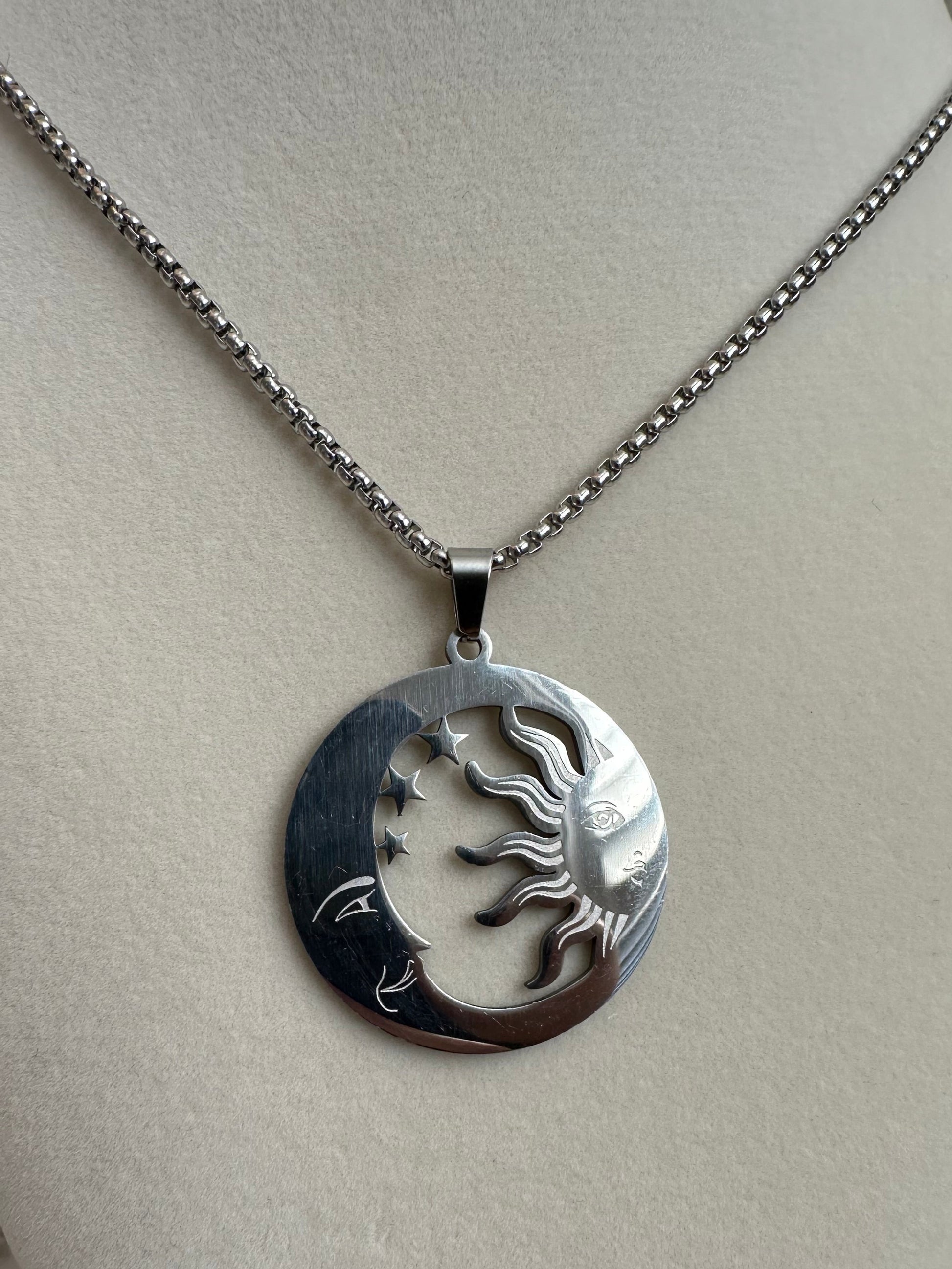 Silver necklace with a sun and moon pendant on a mannequin bust.