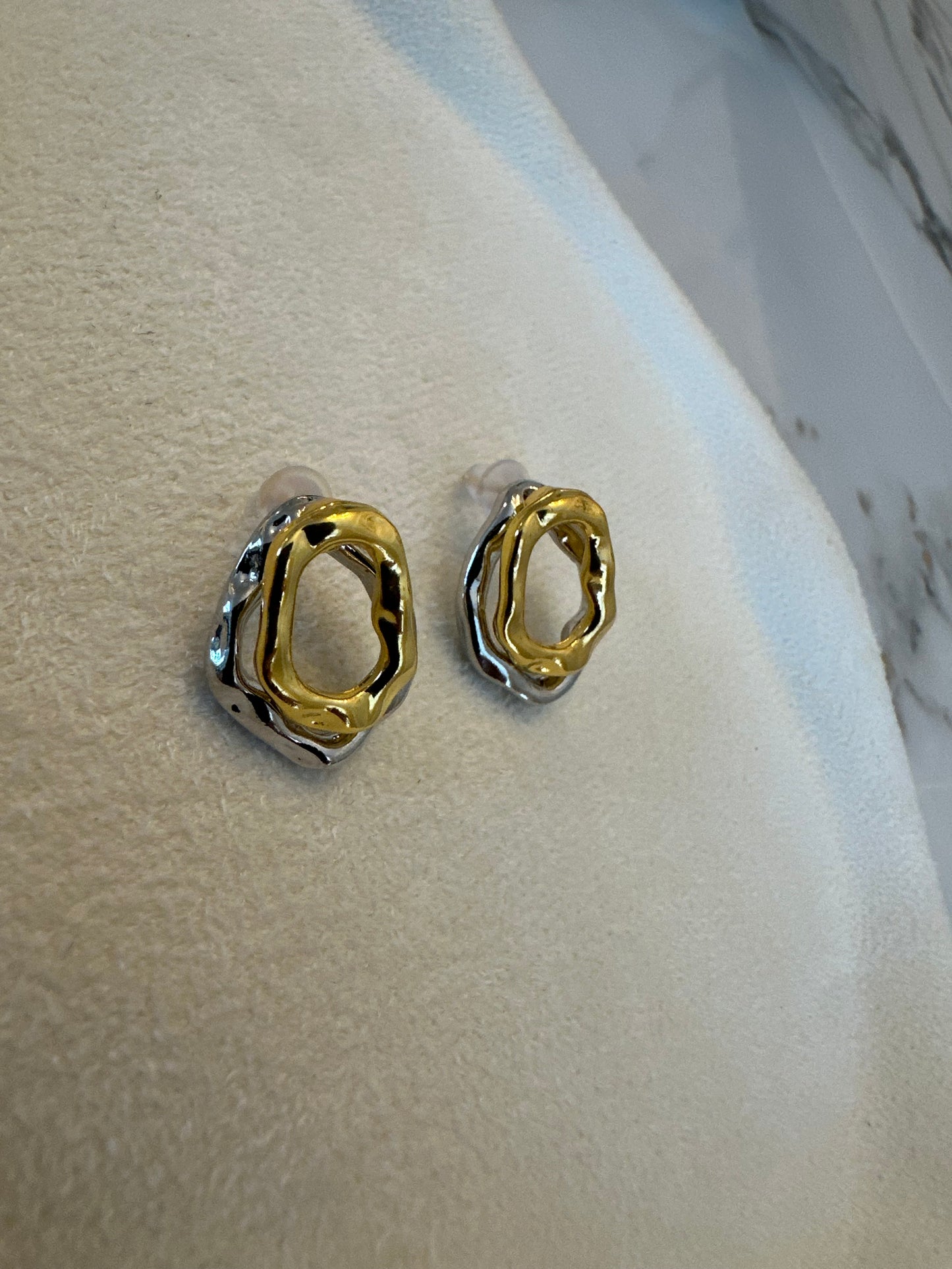 Gold hoop earrings on a marble surface