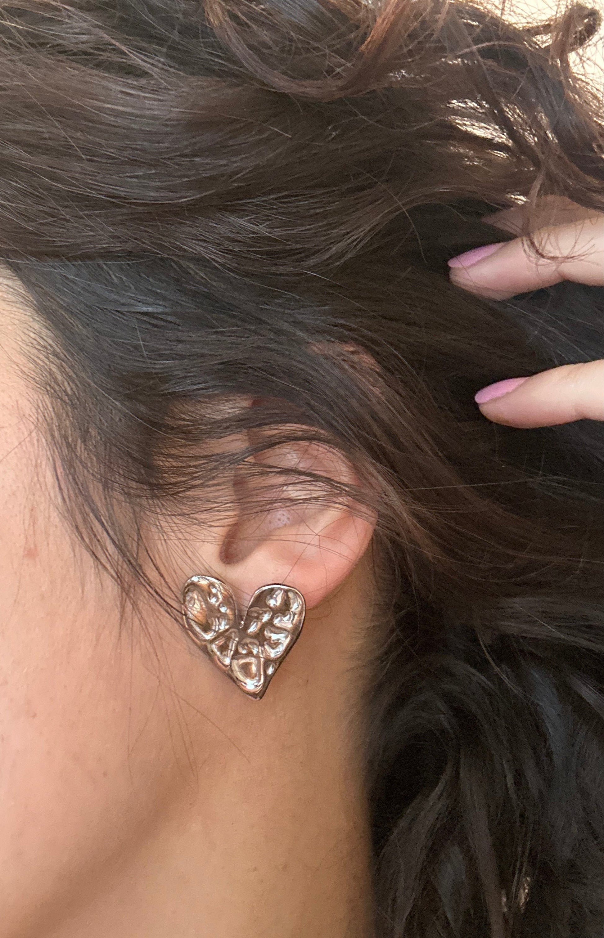 Close-up of an ear with a decorative earring, hair partially covering the face.