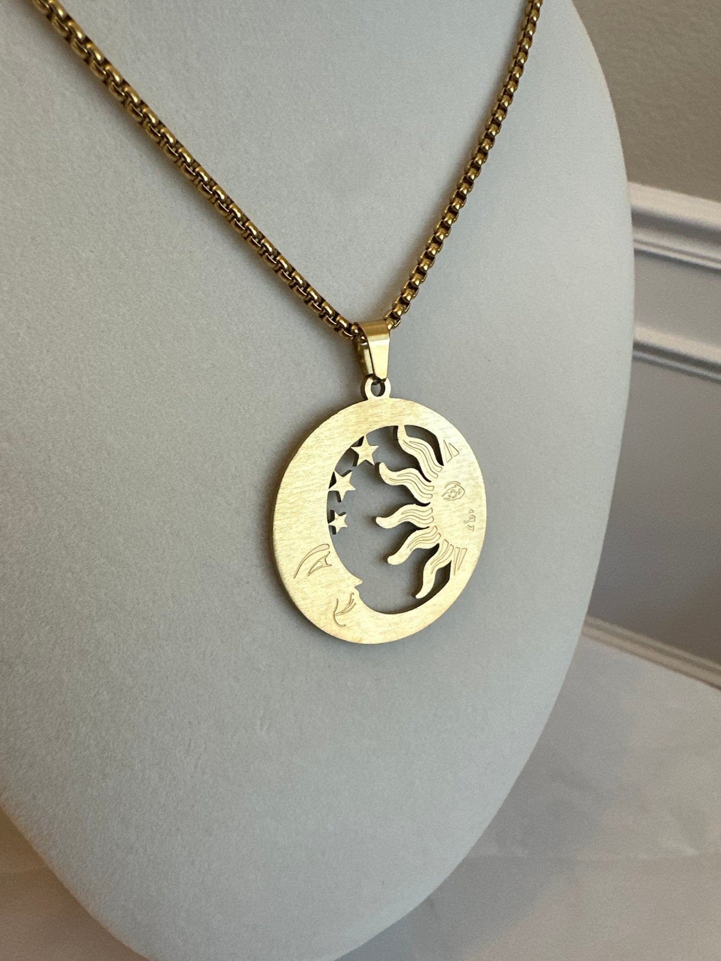 Gold necklace with a decorative pendant on a light gray surface