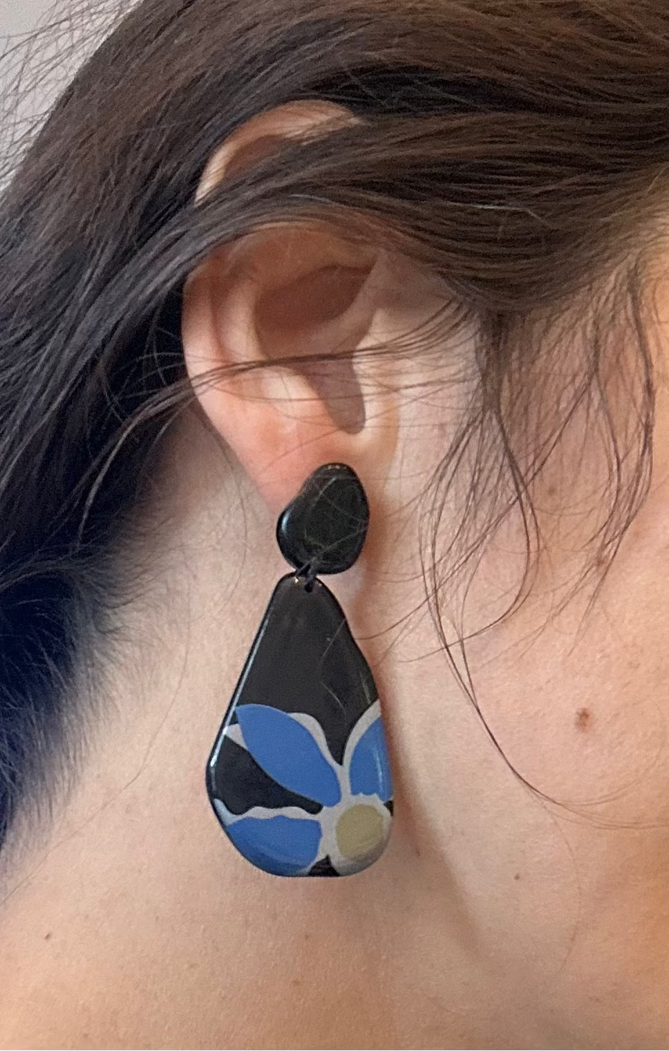 Close-up of an ear wearing a black and blue floral earring.