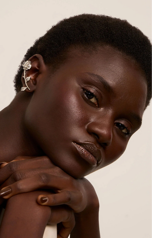 Woman with a short haircut wearing an earring against a neutral background