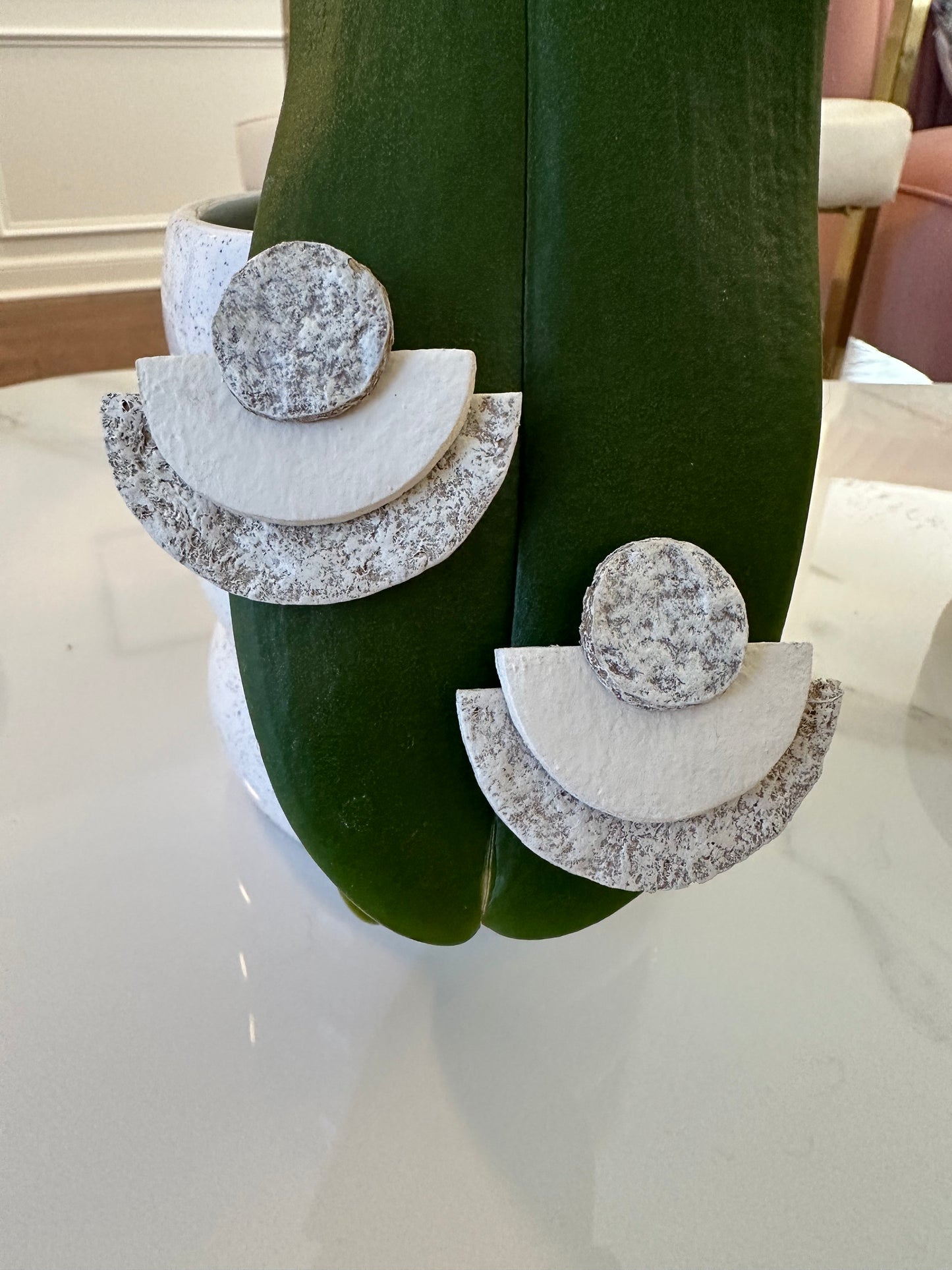 Earrings with geometric design on a green stand