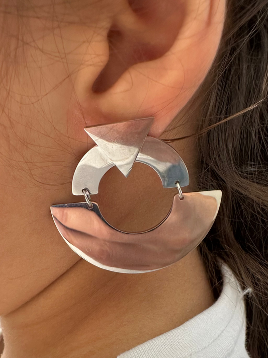 Close-up of a person wearing a unique silver earring with a white background