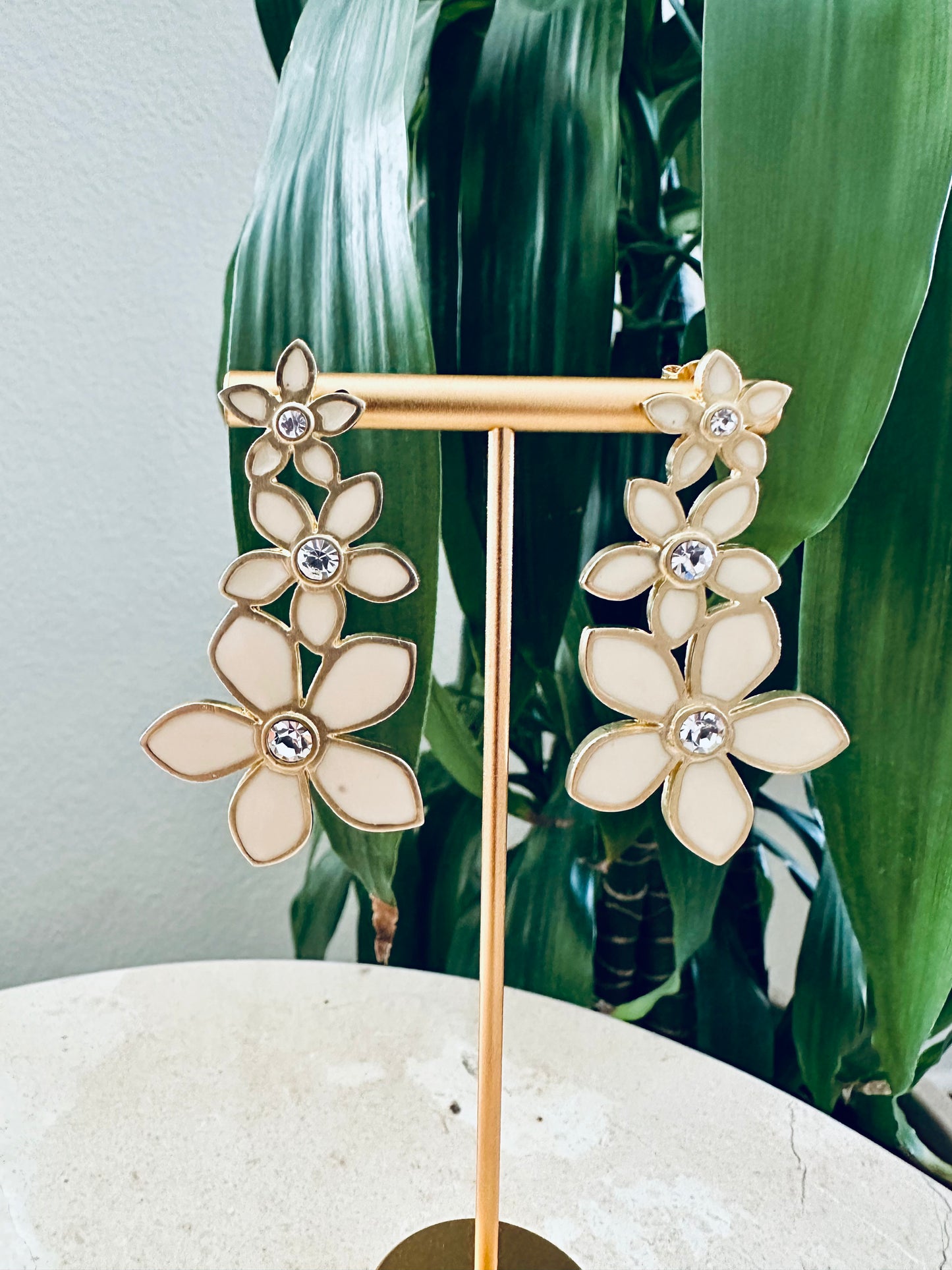 Floral earrings on a stand with a green leafy background