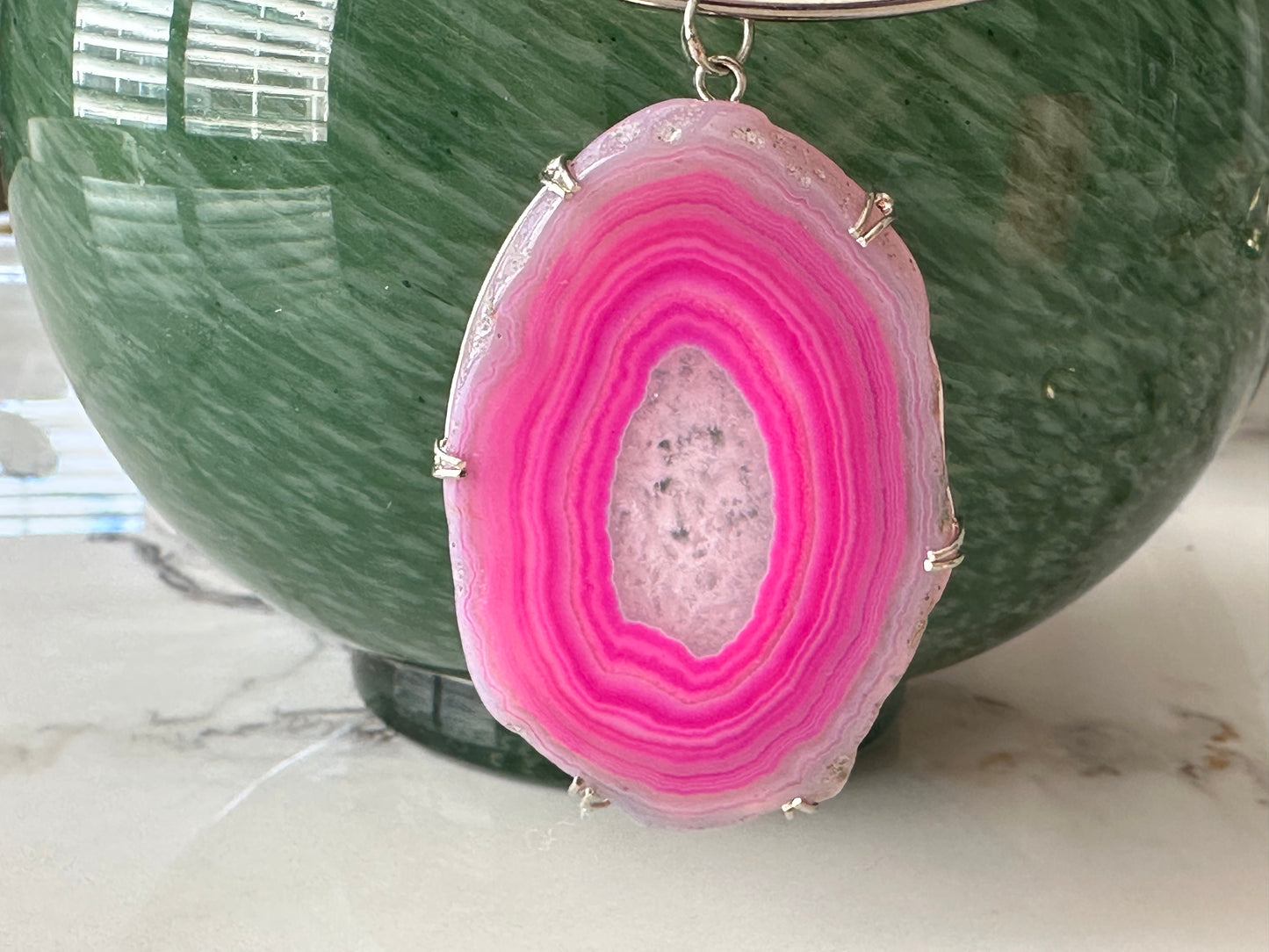 Pink geode pendant on a green marble surface