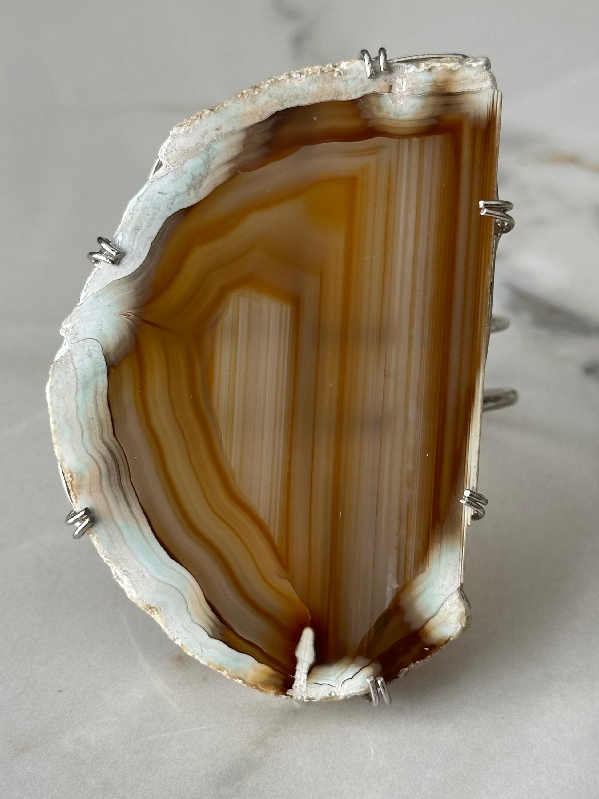 Agate stone with silver setting on a light gray background