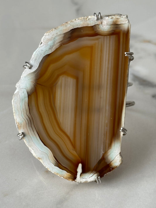 Agate stone with silver setting on a light gray background