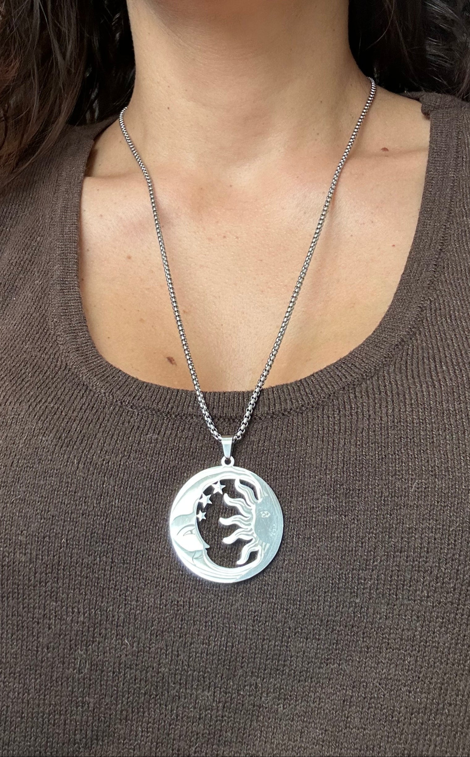 Person wearing a necklace with a silver pendant