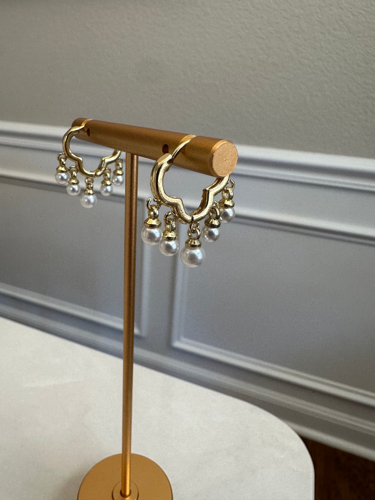 Gold decorative wall hook with pearl-like accents on a neutral background