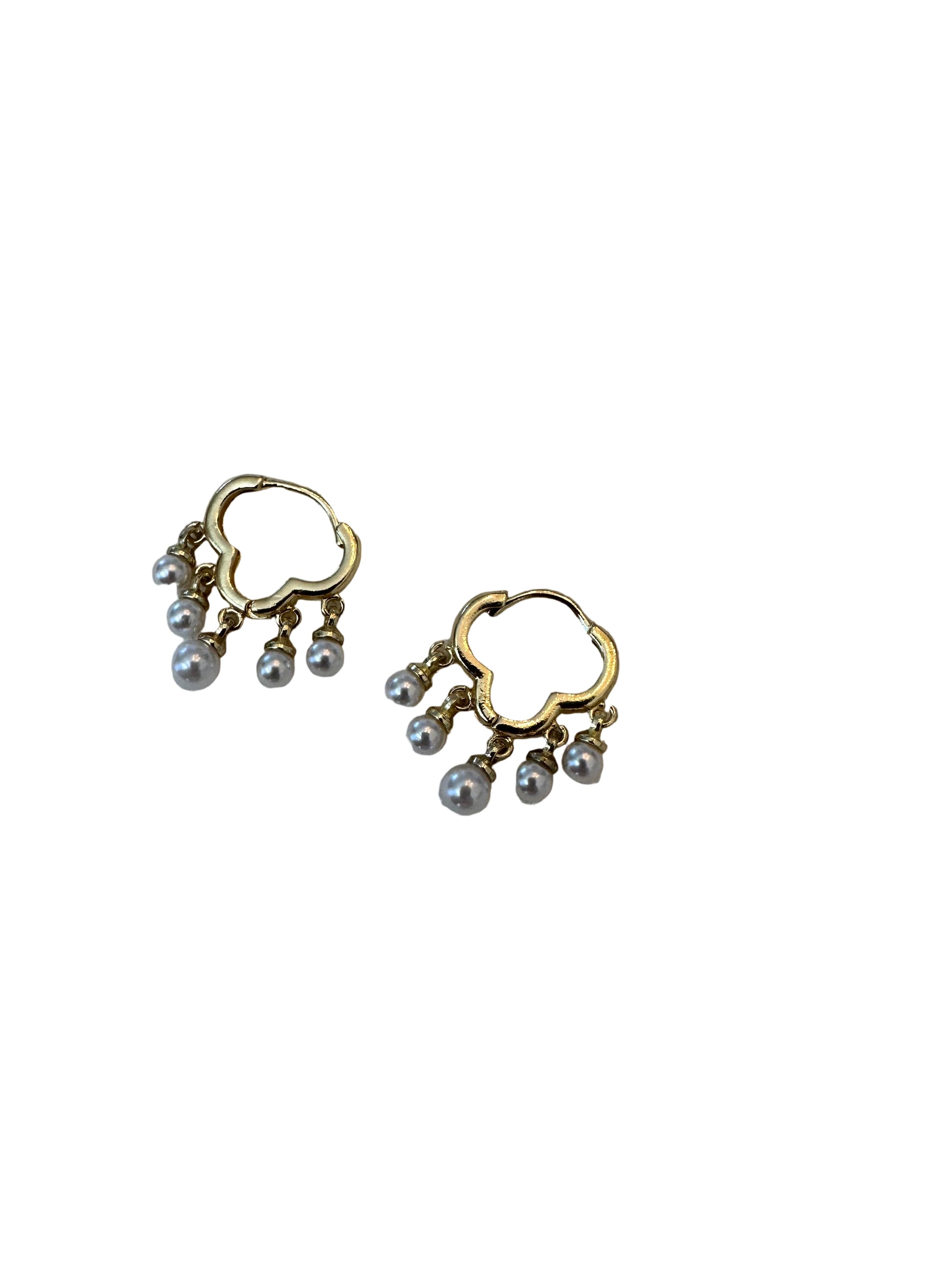 Gold heart-shaped earrings with pearl-like beads on a light fabric background
