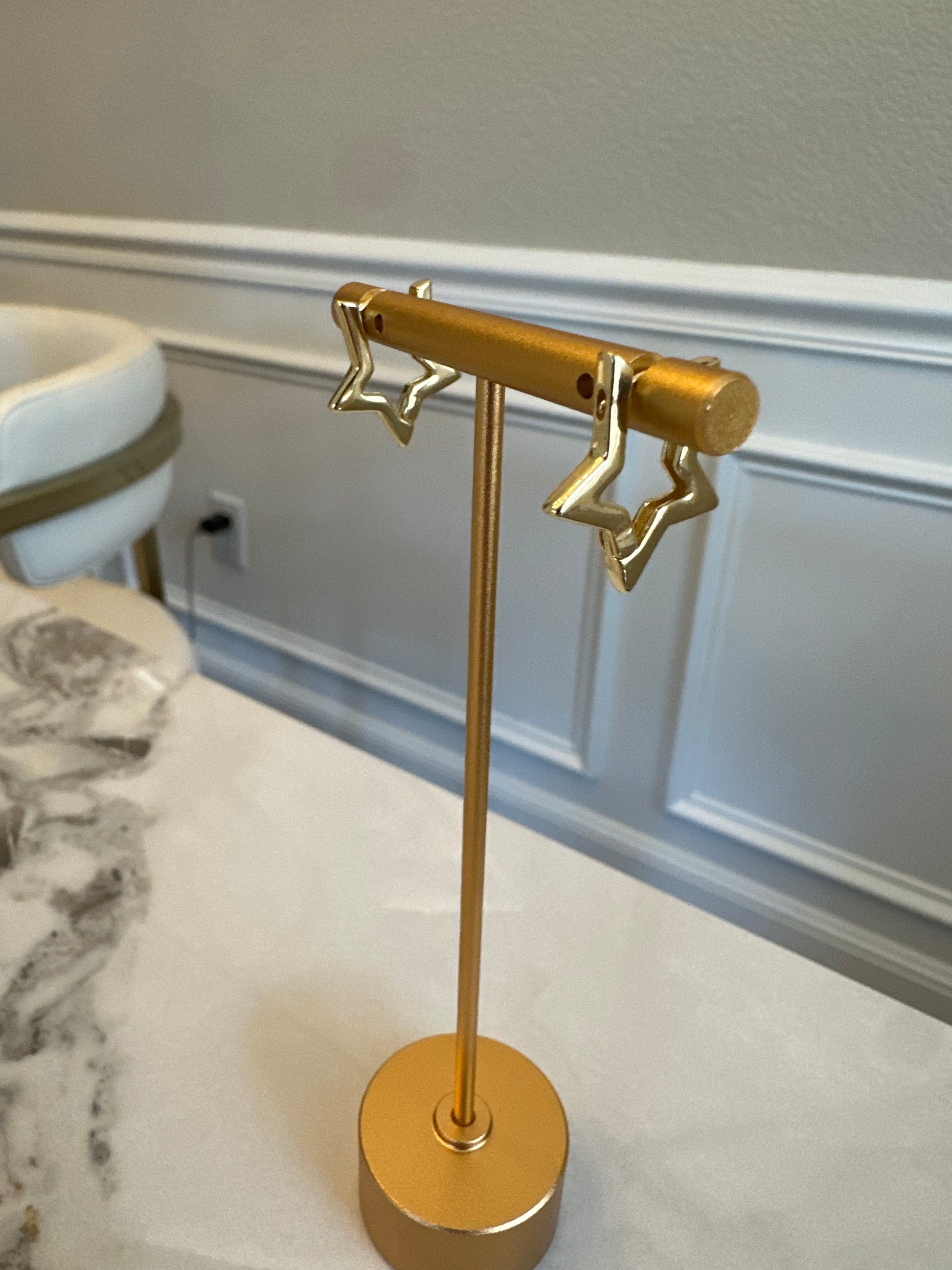 Gold wall-mounted lamp with star design on a white wall.