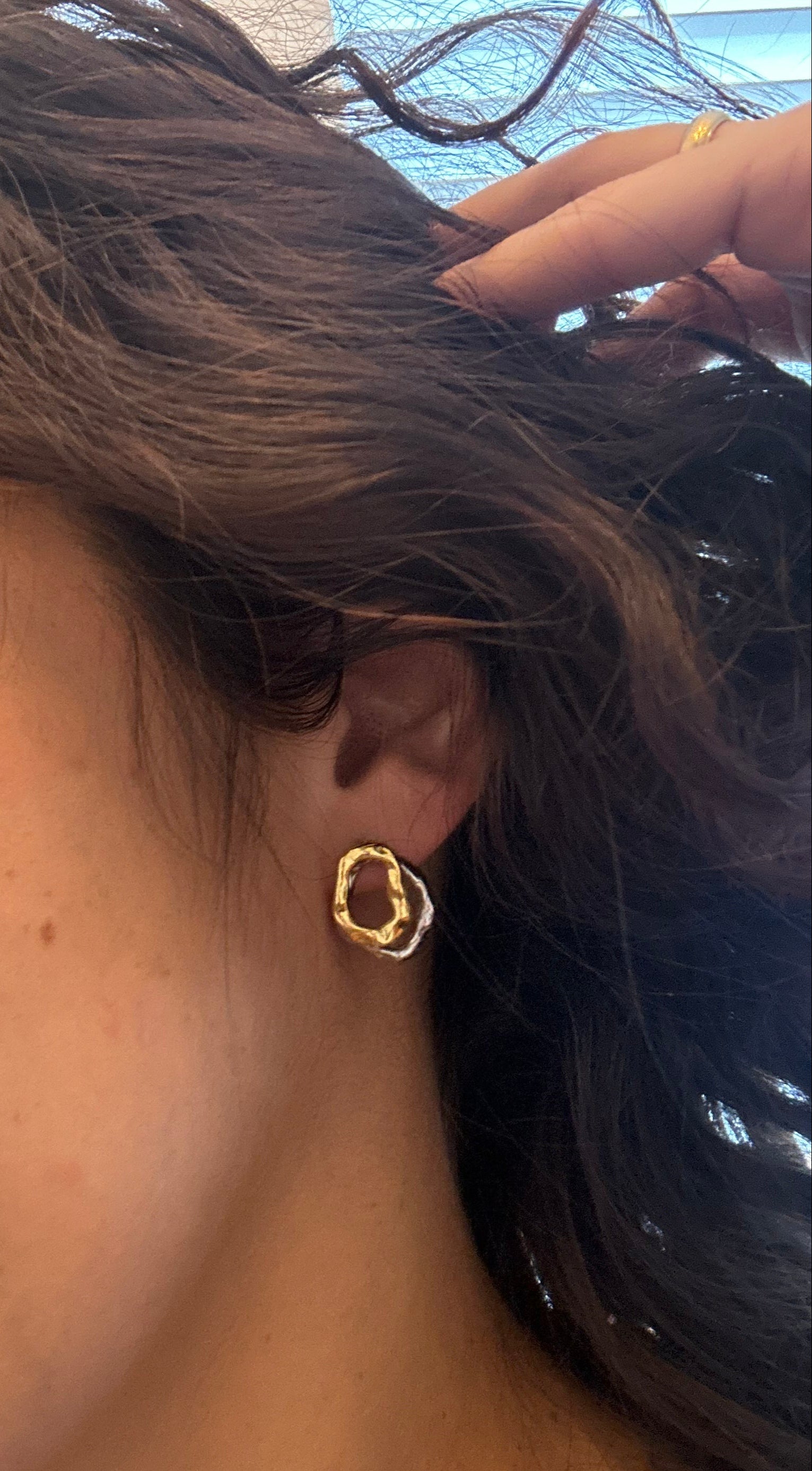 Close-up of a person wearing a gold earring outdoors