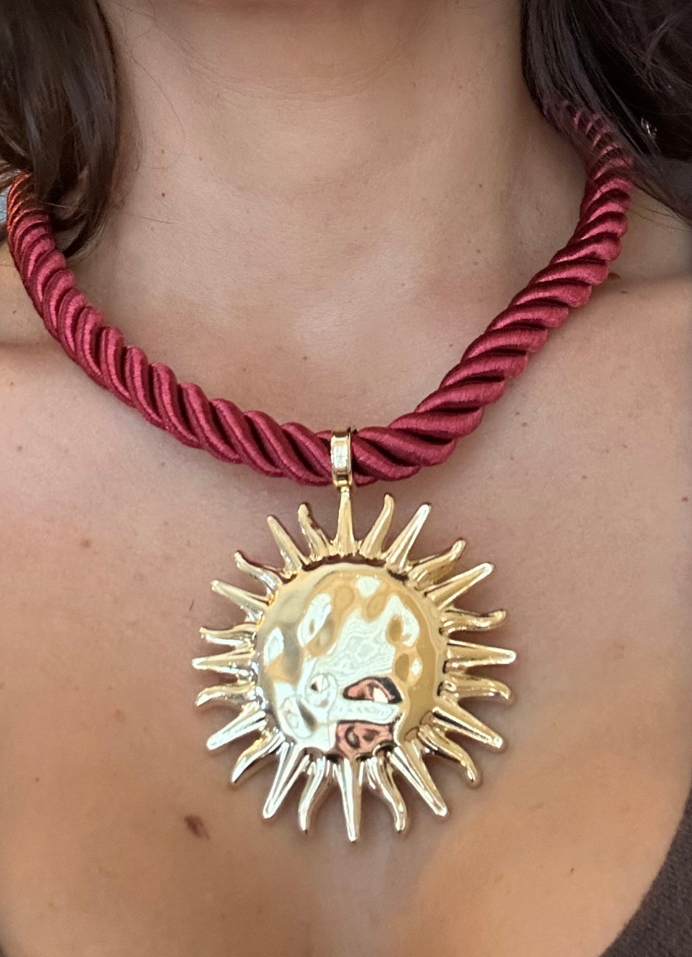 Close-up of a person wearing a red braided headband and gold sun-shaped hair accessory.