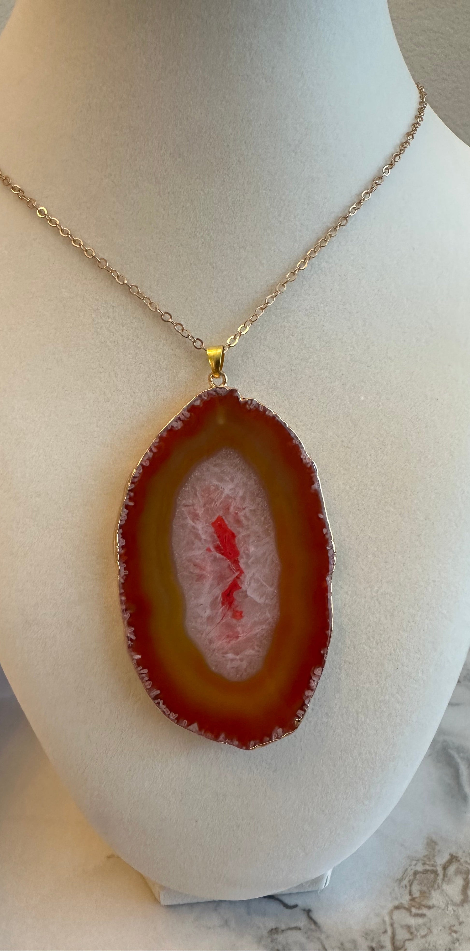 Necklace with a red agate pendant on a mannequin bust.