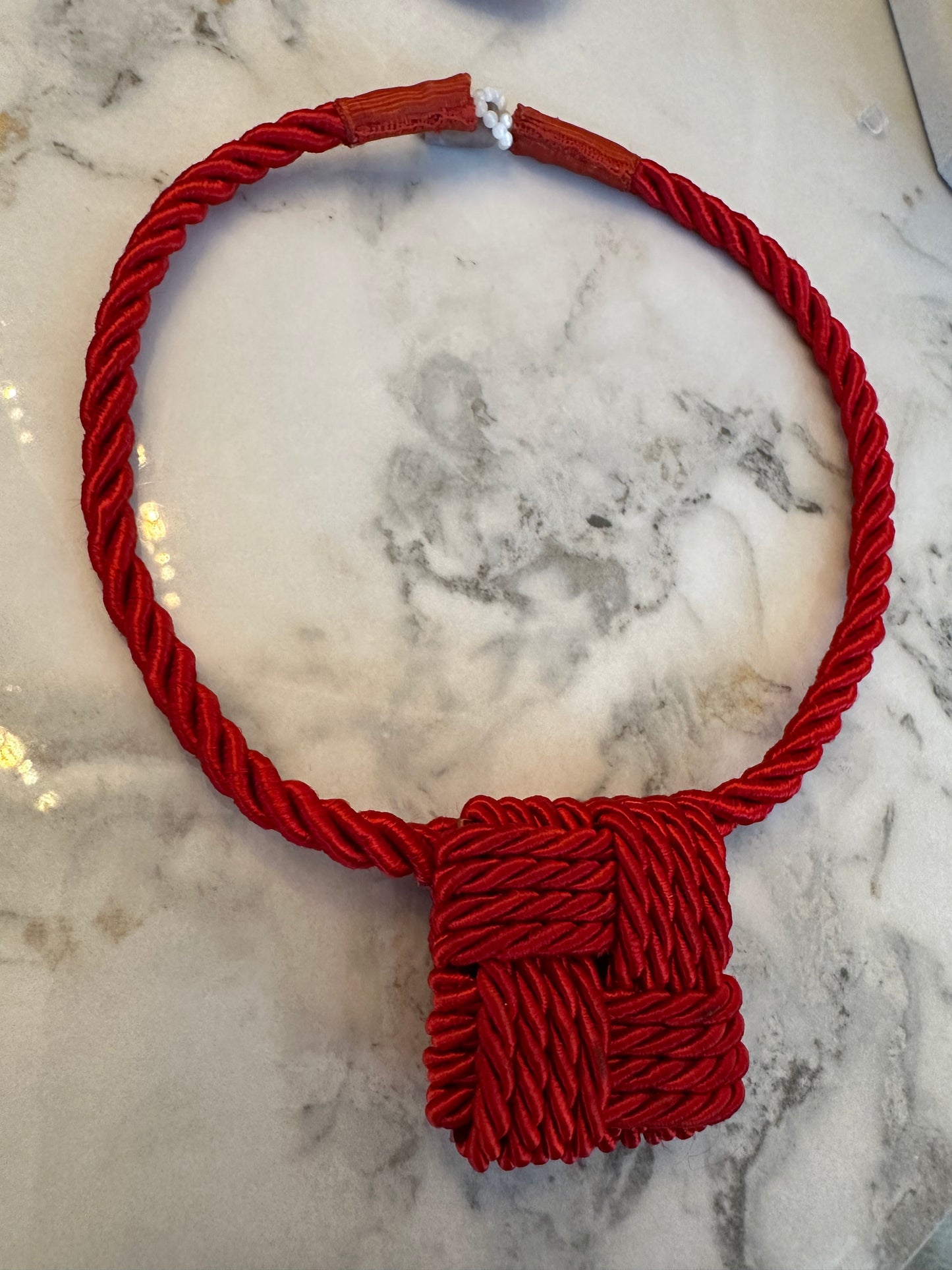 Red rope with a knot on a marble surface