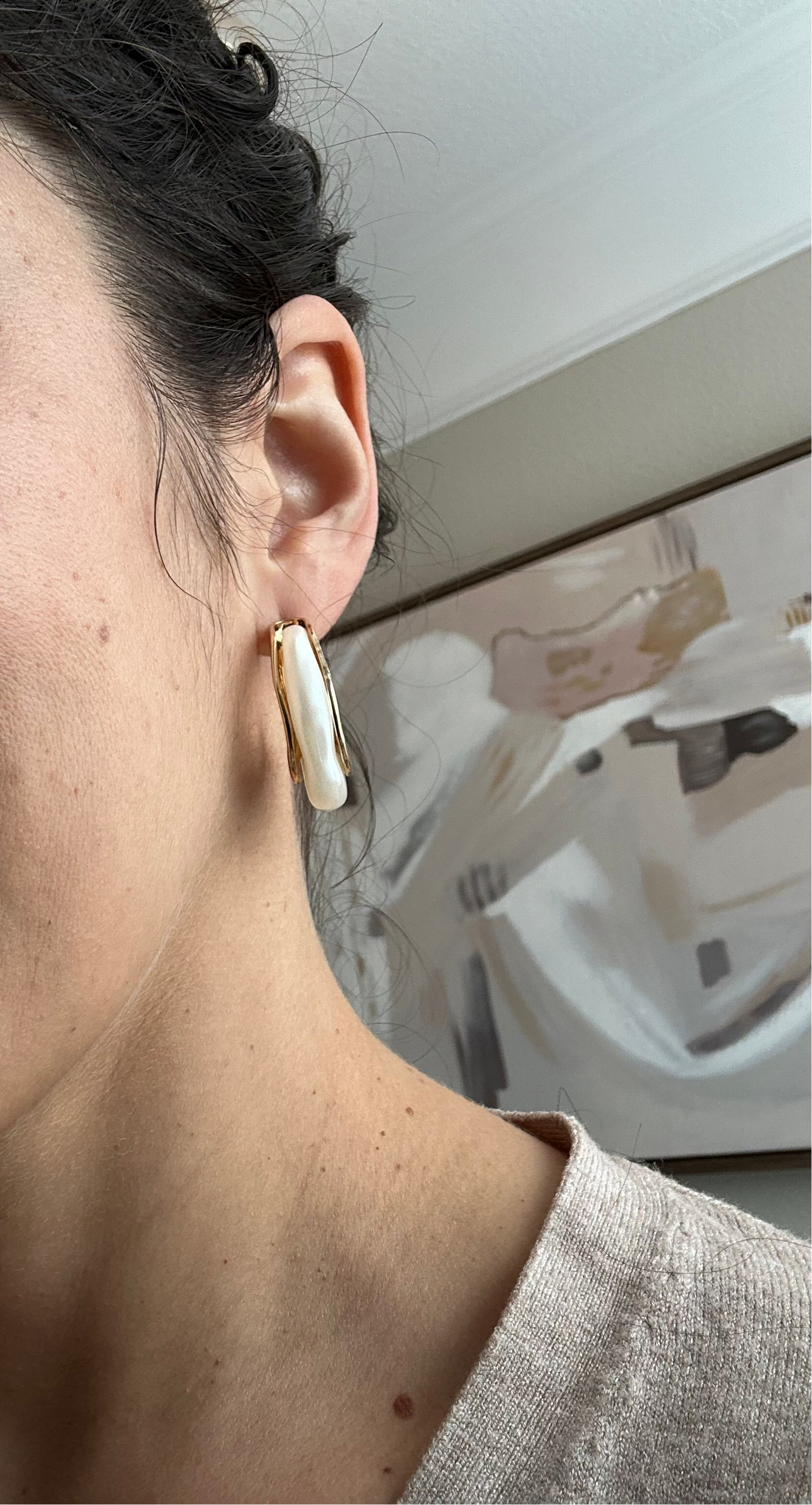 Close-up of a person wearing a gold earring with a blurred background