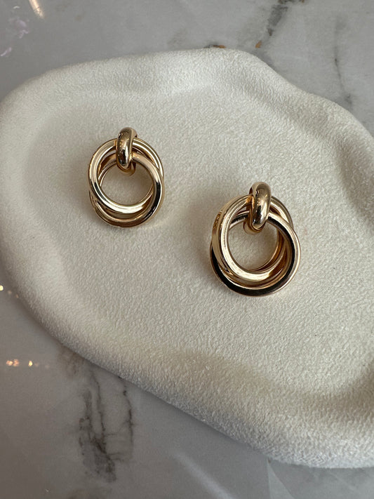 Gold hoop earrings on a white cushion with a marble background