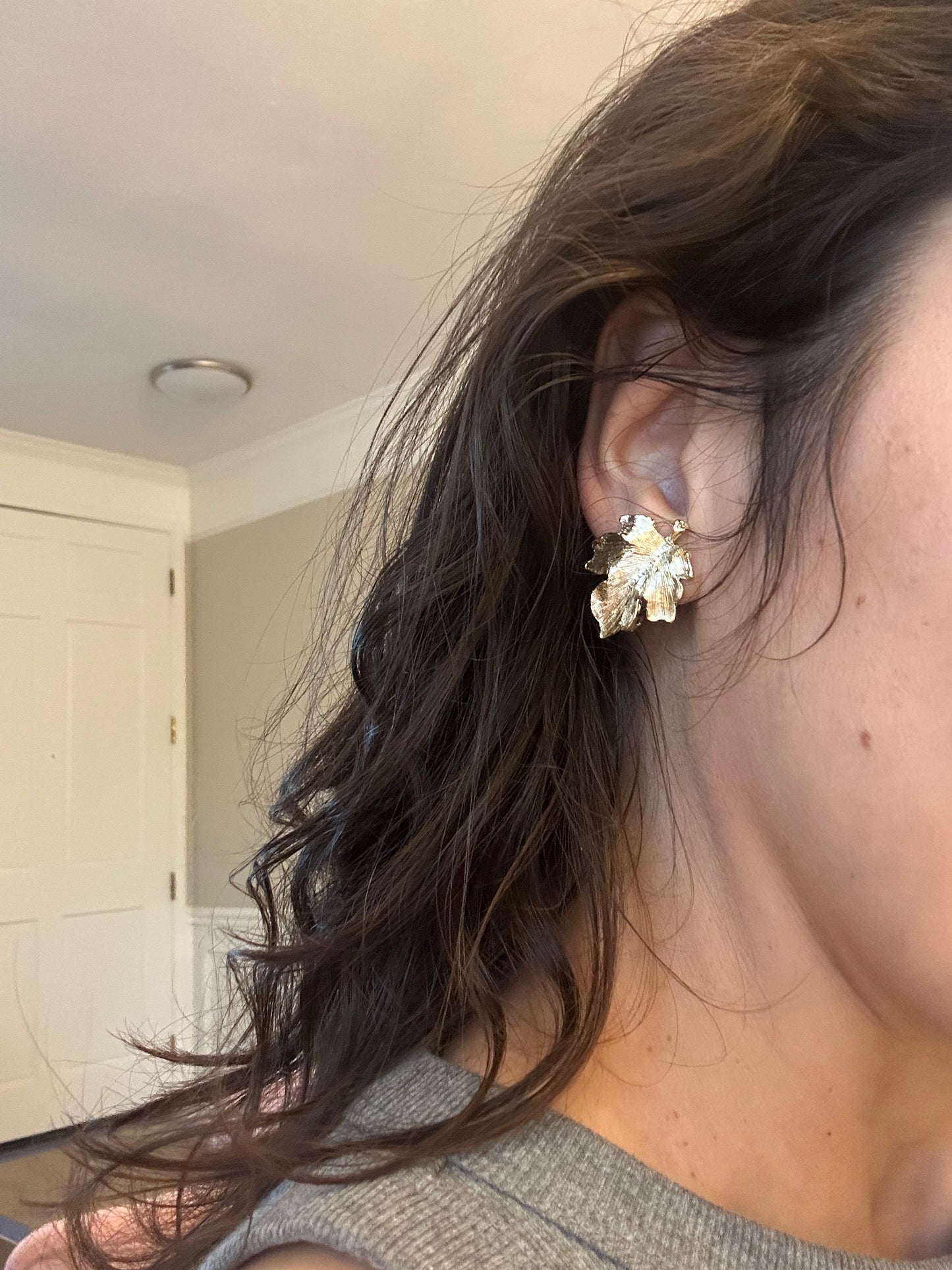 Close-up of an ear wearing a floral earring with a blurred background