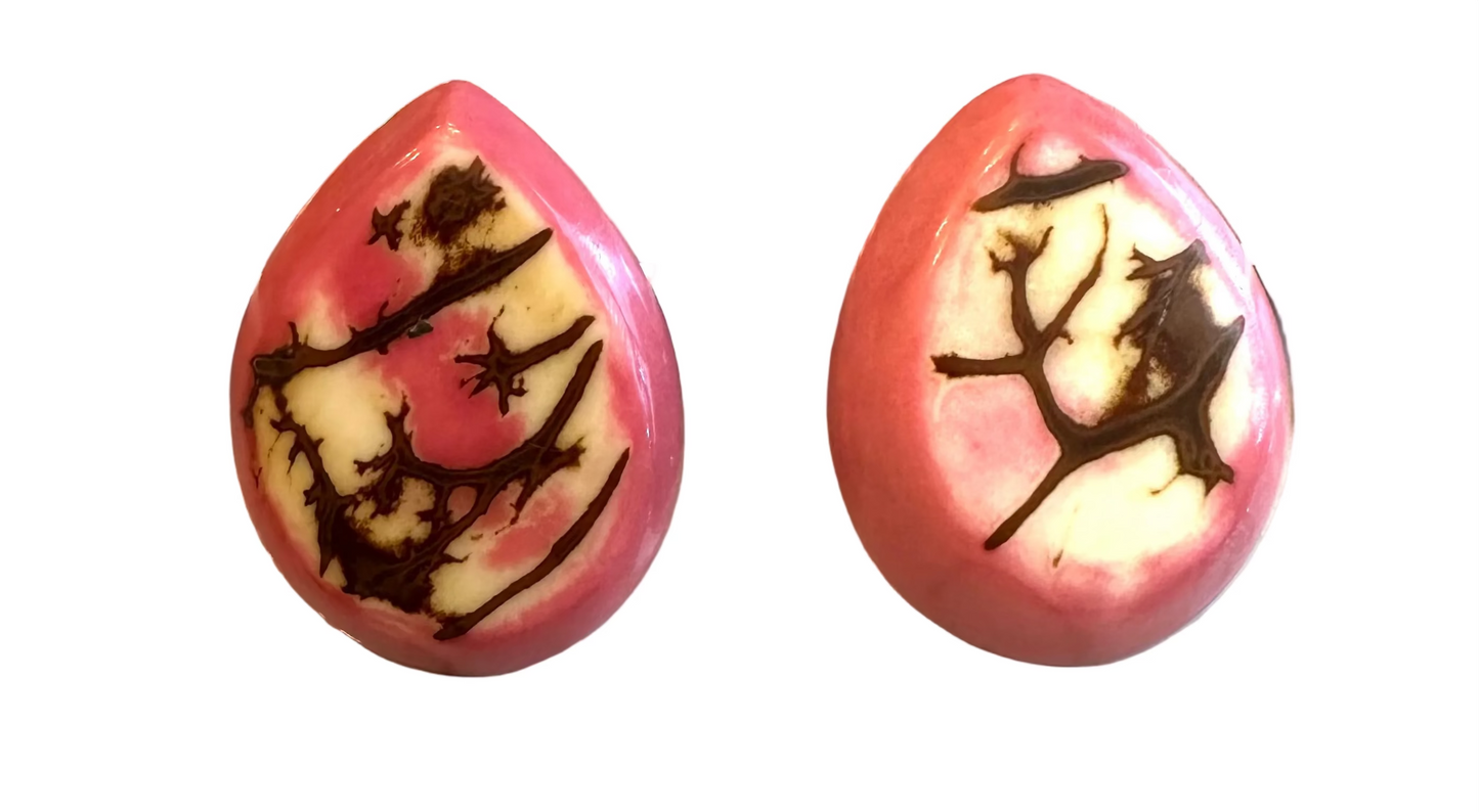 Two pink teardrop-shaped objects with black designs on a digital scale.