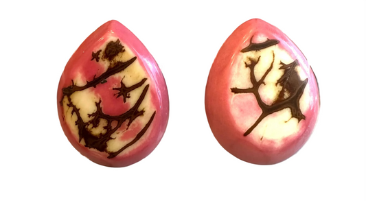 Two pink teardrop-shaped objects with black designs on a digital scale.