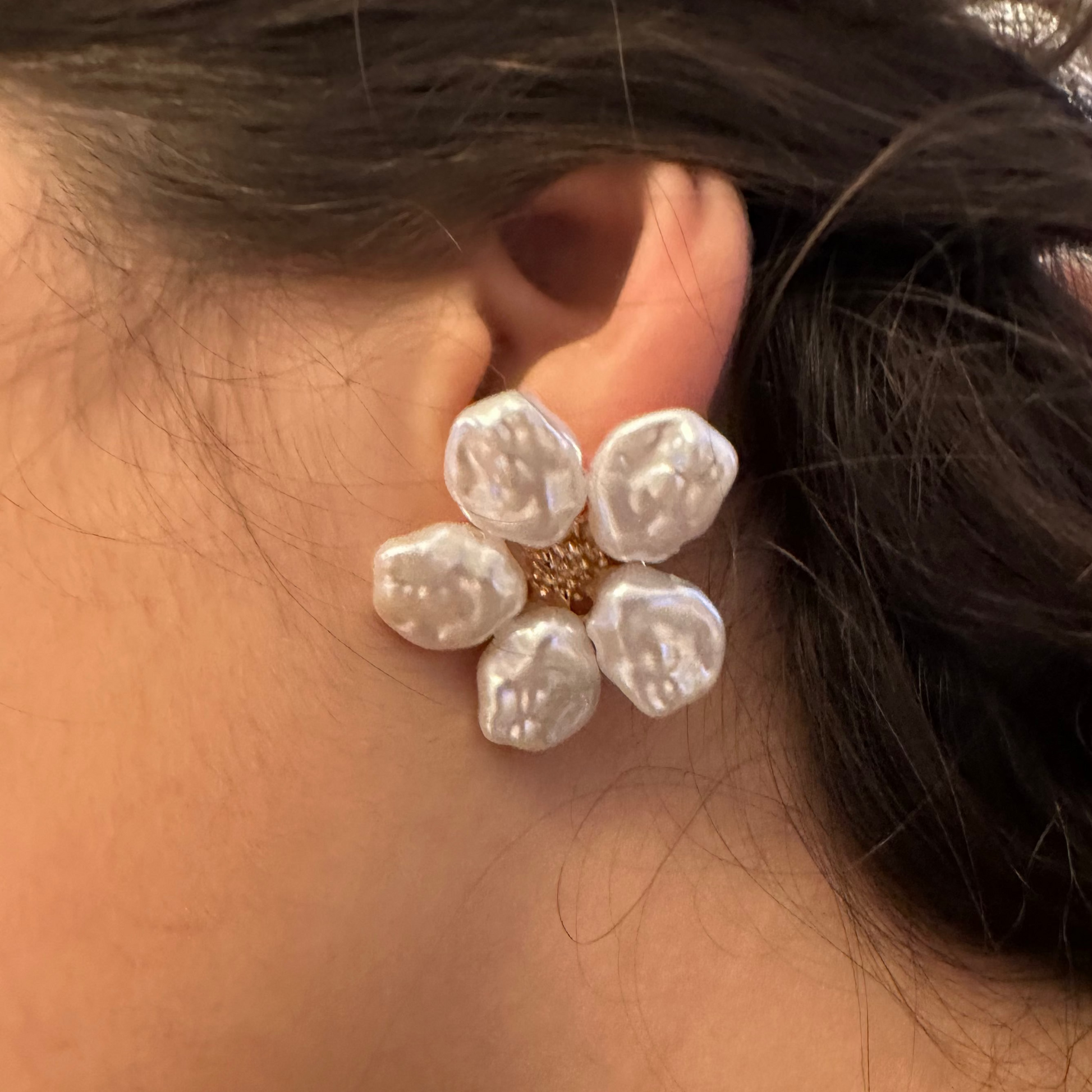 Close-up of a person wearing a floral earring with a blurred background