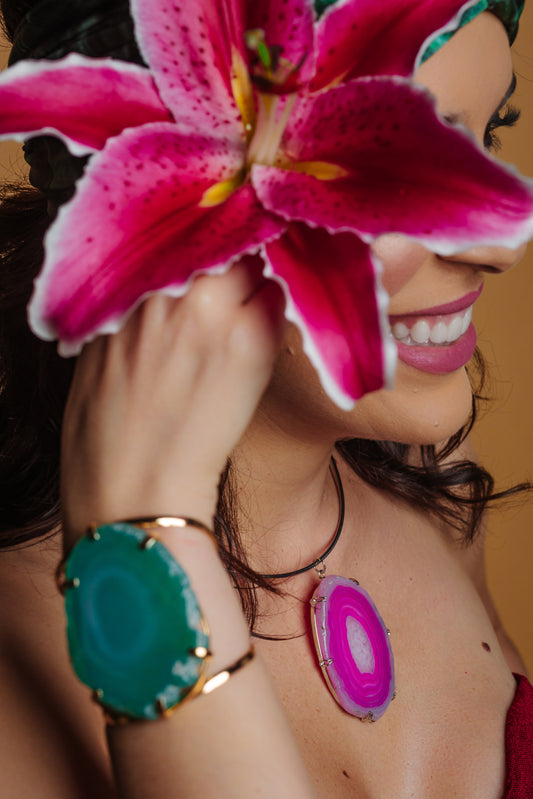 Woman holding a pink flower in front of her face with a blurred background