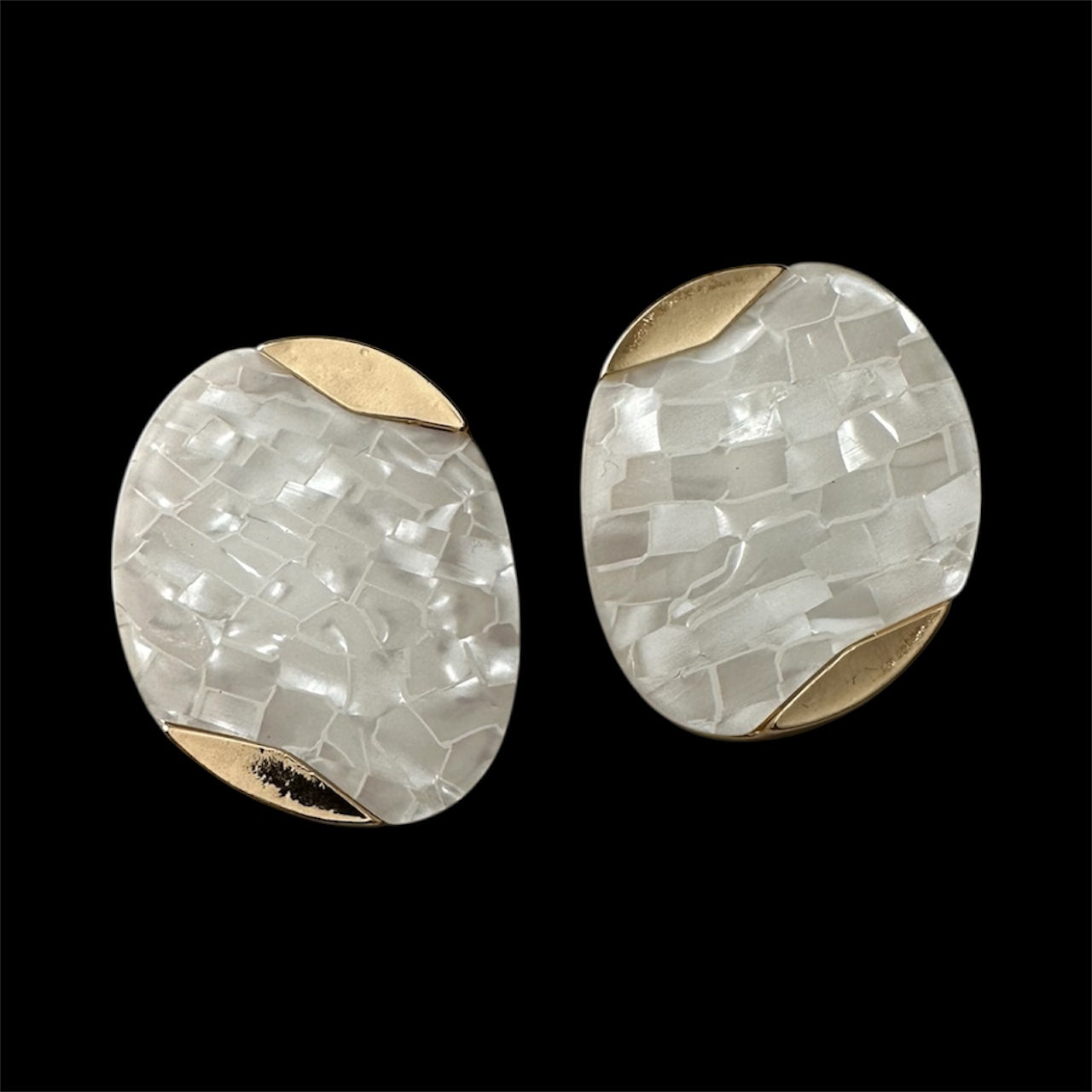 Pair of round earrings with mosaic pattern and gold accents on a black background