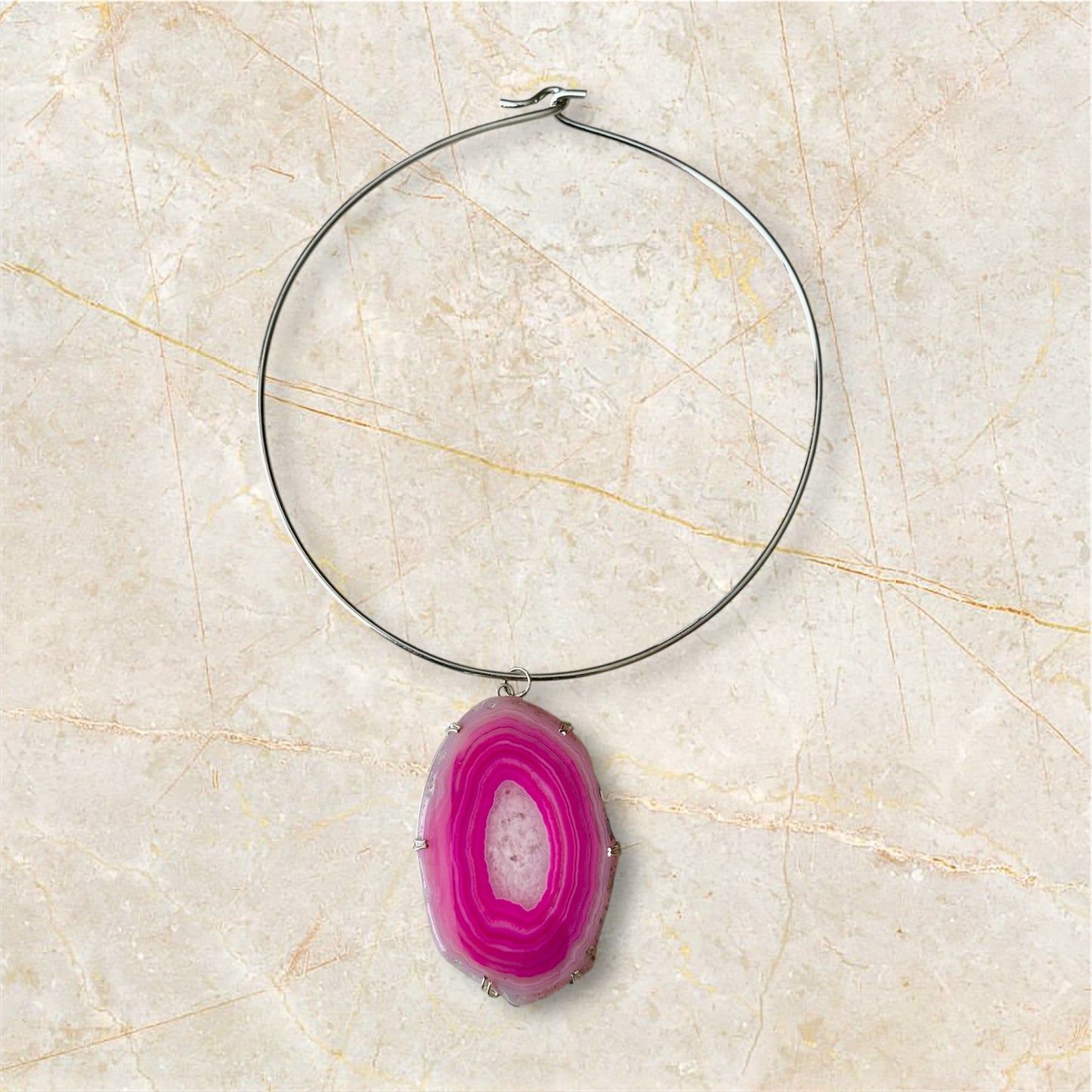 Necklace with a pink agate pendant on a beige marble background