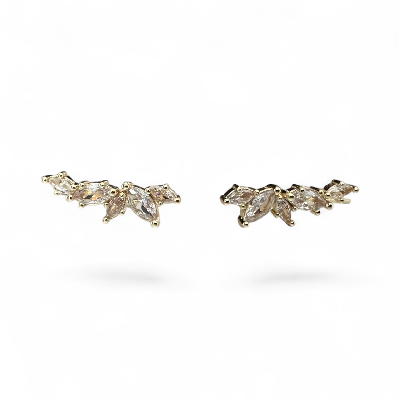 Pair of gold earrings with clear gemstones on a white background