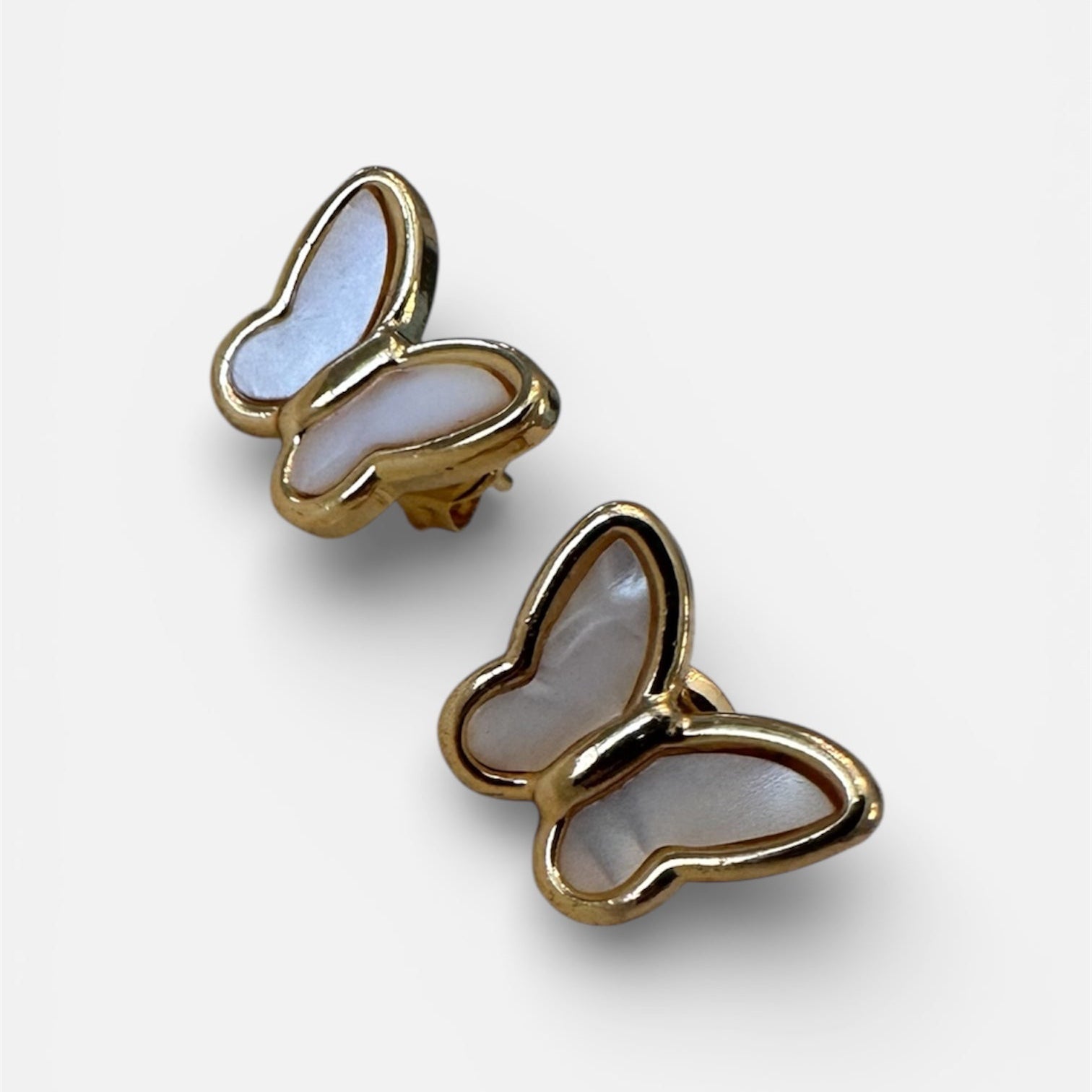 Butterfly-shaped earrings with gold frame and light blue center on a white background