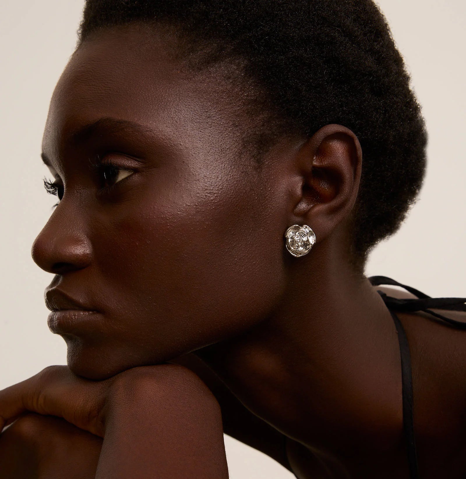 Woman wearing a diamond earring against a neutral background